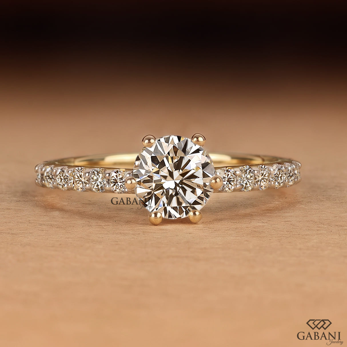 Round cut lab grown diamond solitaire engagement ring in yellow gold featuring a classic six prong setting and pavé diamond band.