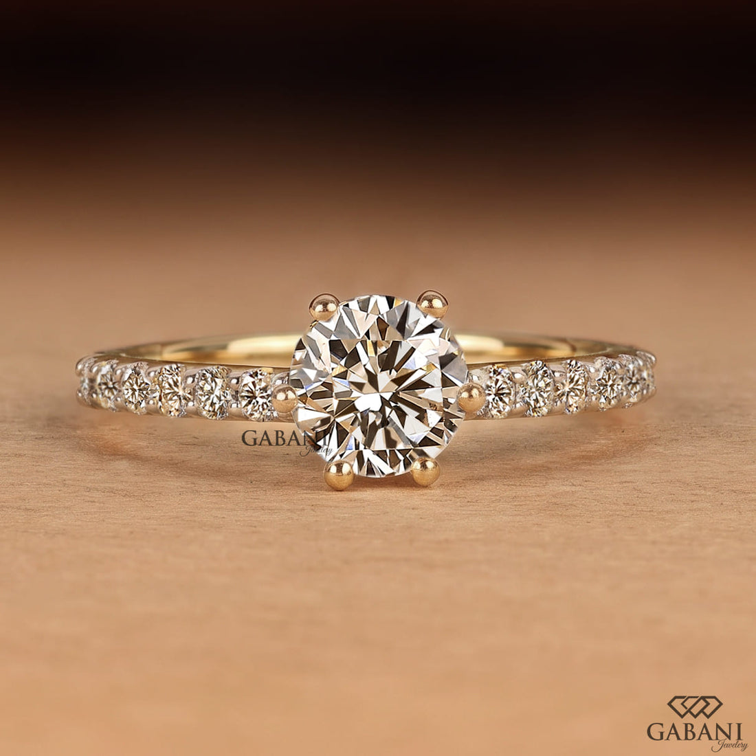Round cut lab grown diamond solitaire engagement ring in yellow gold featuring a classic six prong setting and pavé diamond band.