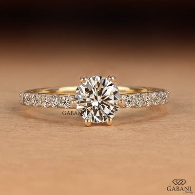 Round cut lab grown diamond solitaire engagement ring in yellow gold featuring a classic six prong setting and pavé diamond band.