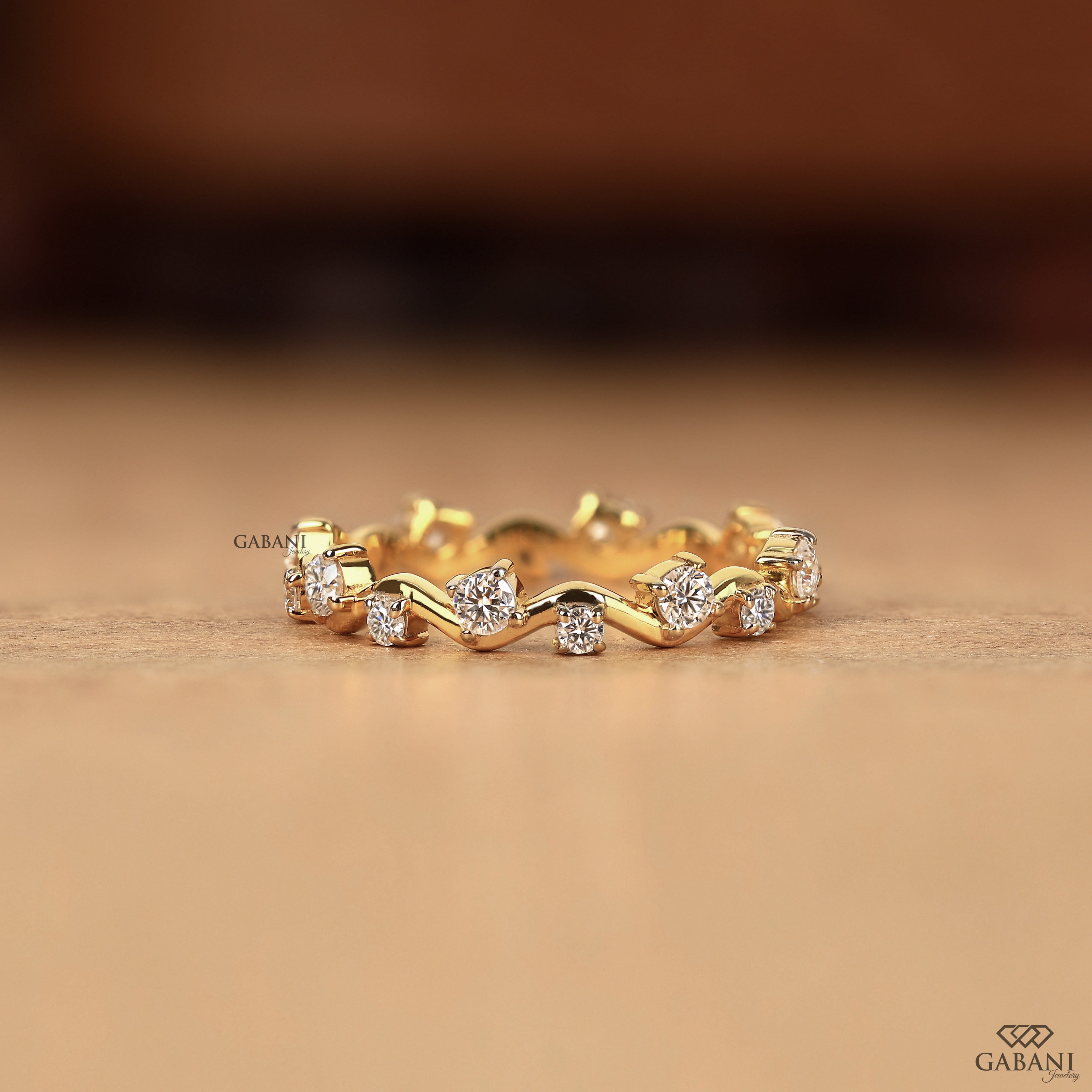 a round lab grown diamond zigzag eternity band in 14K yellow gold, featuring alternating round diamonds in a unique wave design.