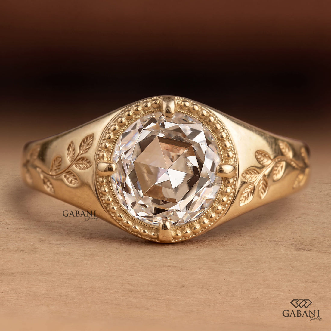 Round rose cut lab grown diamond signet ring with four prong setting, leaf engraving, beaded detailing and yellow gold band.