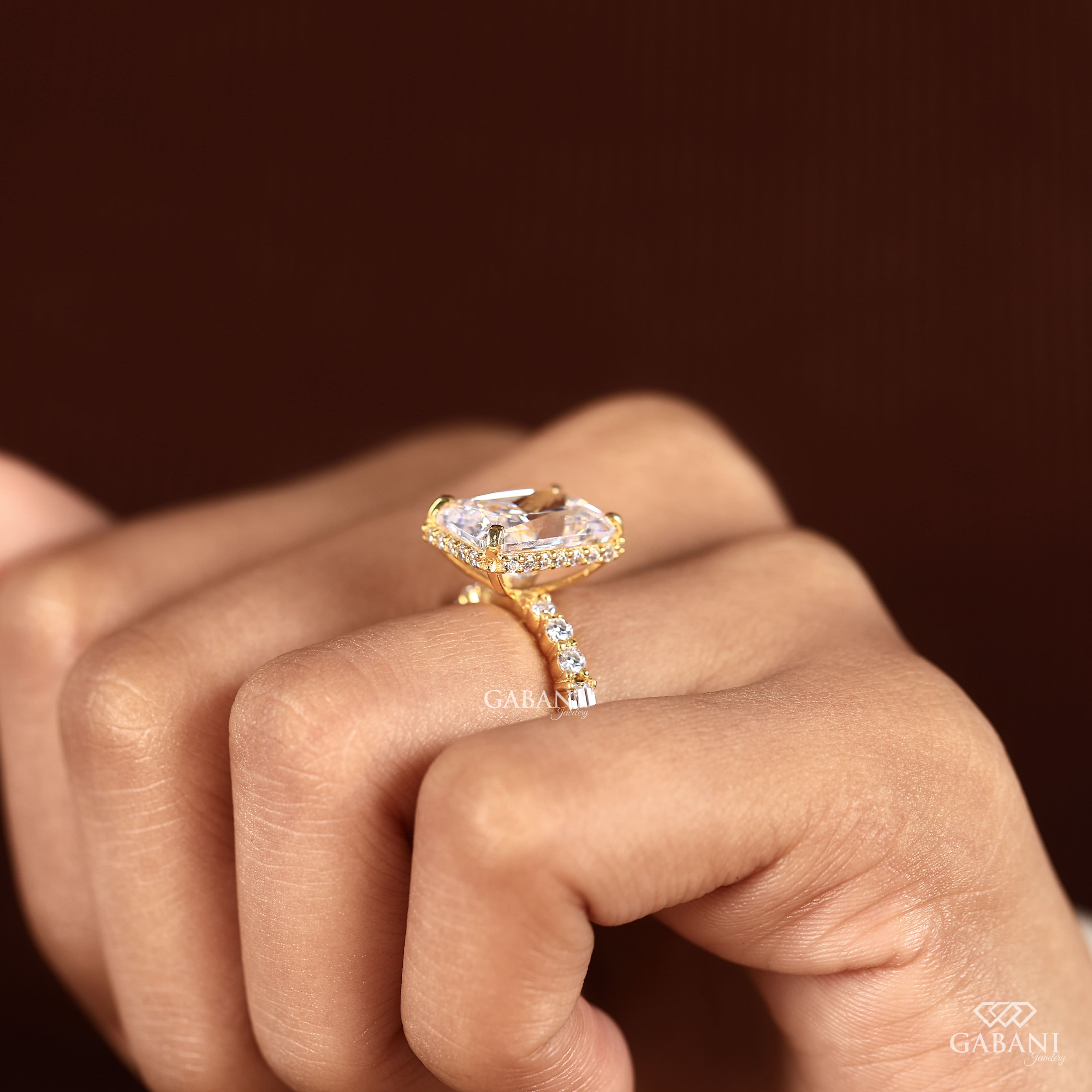 Radiant cut lab grown diamond engagement ring with hidden halo, round and baguette side diamonds, and polished gold band.