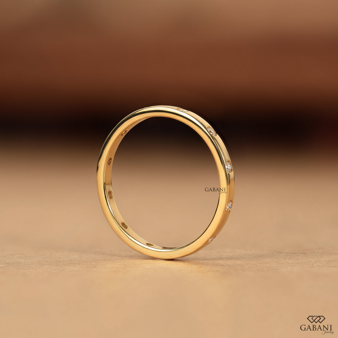 a minimalist lab grown diamond wedding band featuring round cut diamonds individually flush set into polished 14K yellow gold, creating a modern eternity ring perfect for bridal stacking.
