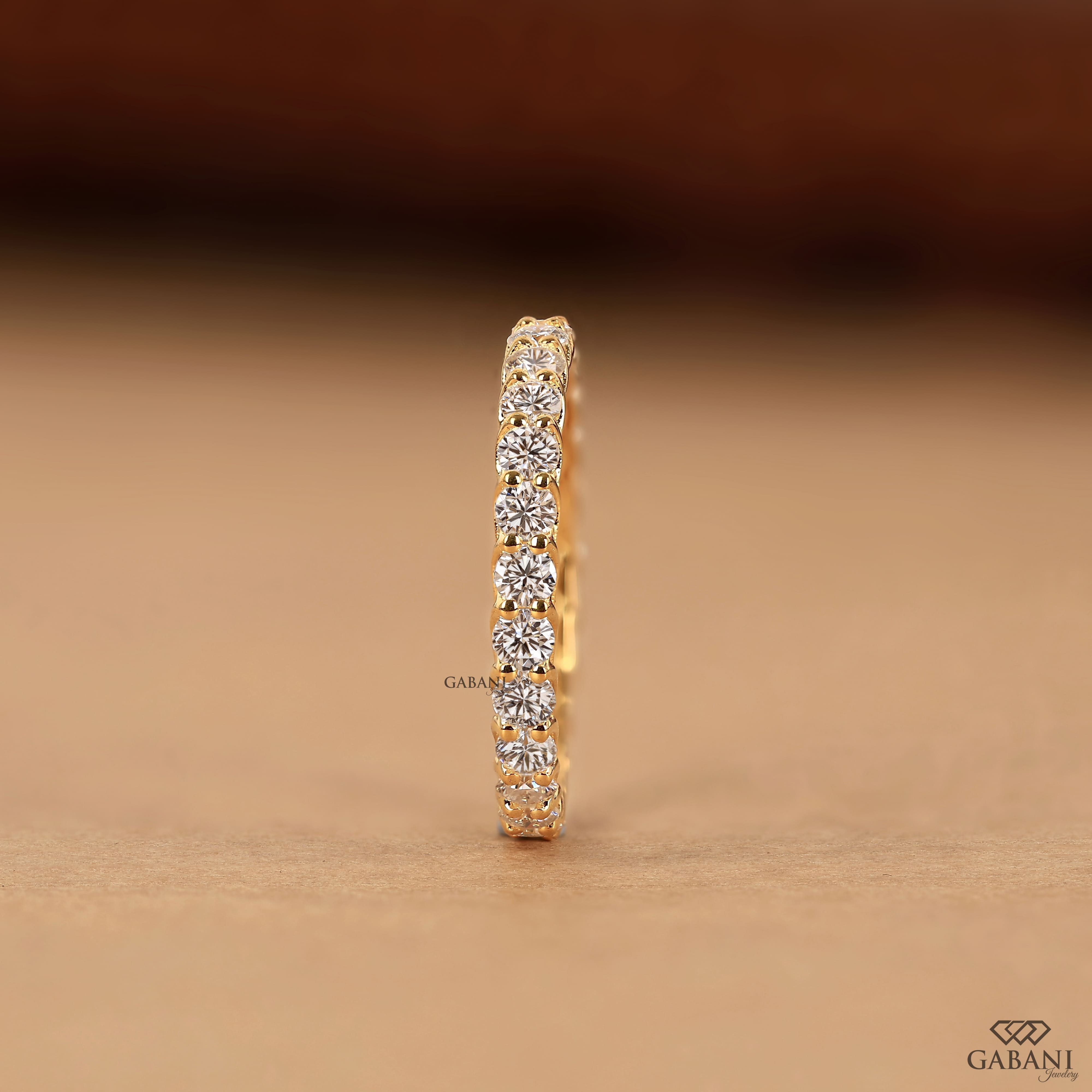 a round lab grown diamond full eternity band in 14K yellow gold, featuring sparkling shared prong set diamonds in a classic wedding band design by Gabani Jewelry.