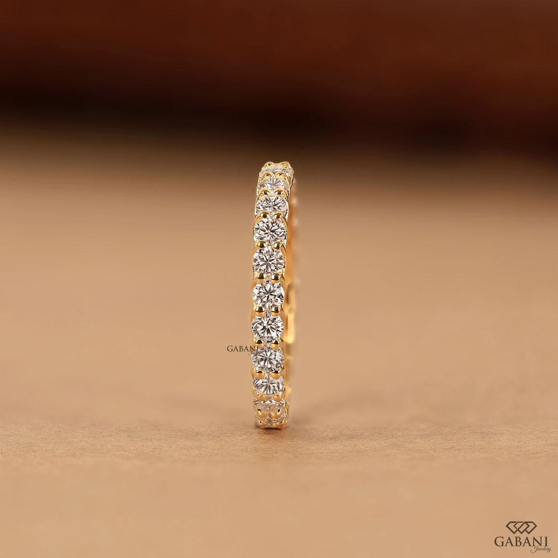 a round lab grown diamond full eternity band in 14K yellow gold, featuring sparkling shared prong set diamonds in a classic wedding band design by Gabani Jewelry.