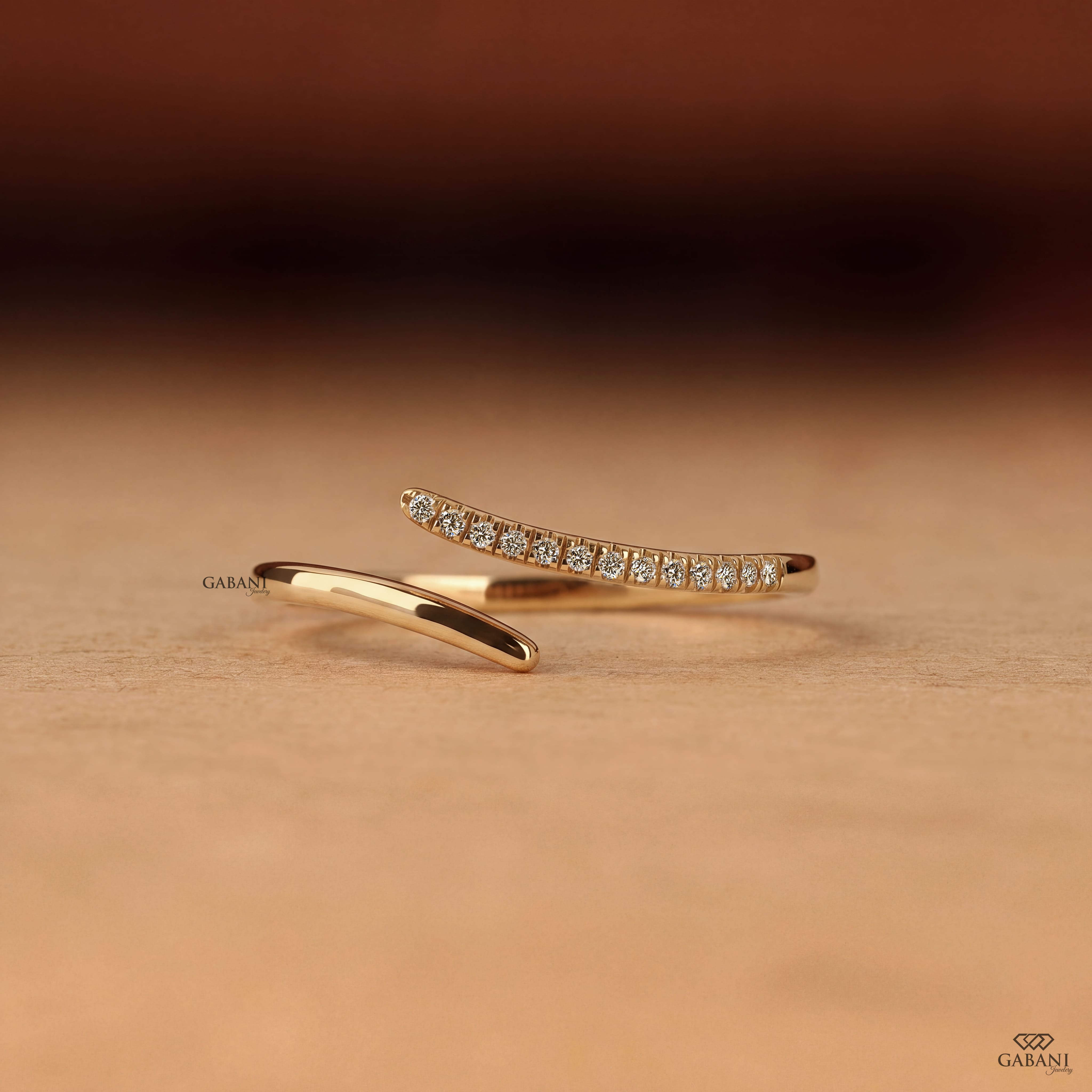 a round lab grown diamond open cuff bangle bracelet in 14K yellow gold, featuring sparkling round diamonds along one curved end and a smooth polished gold wrap design by Gabani Jewelry.