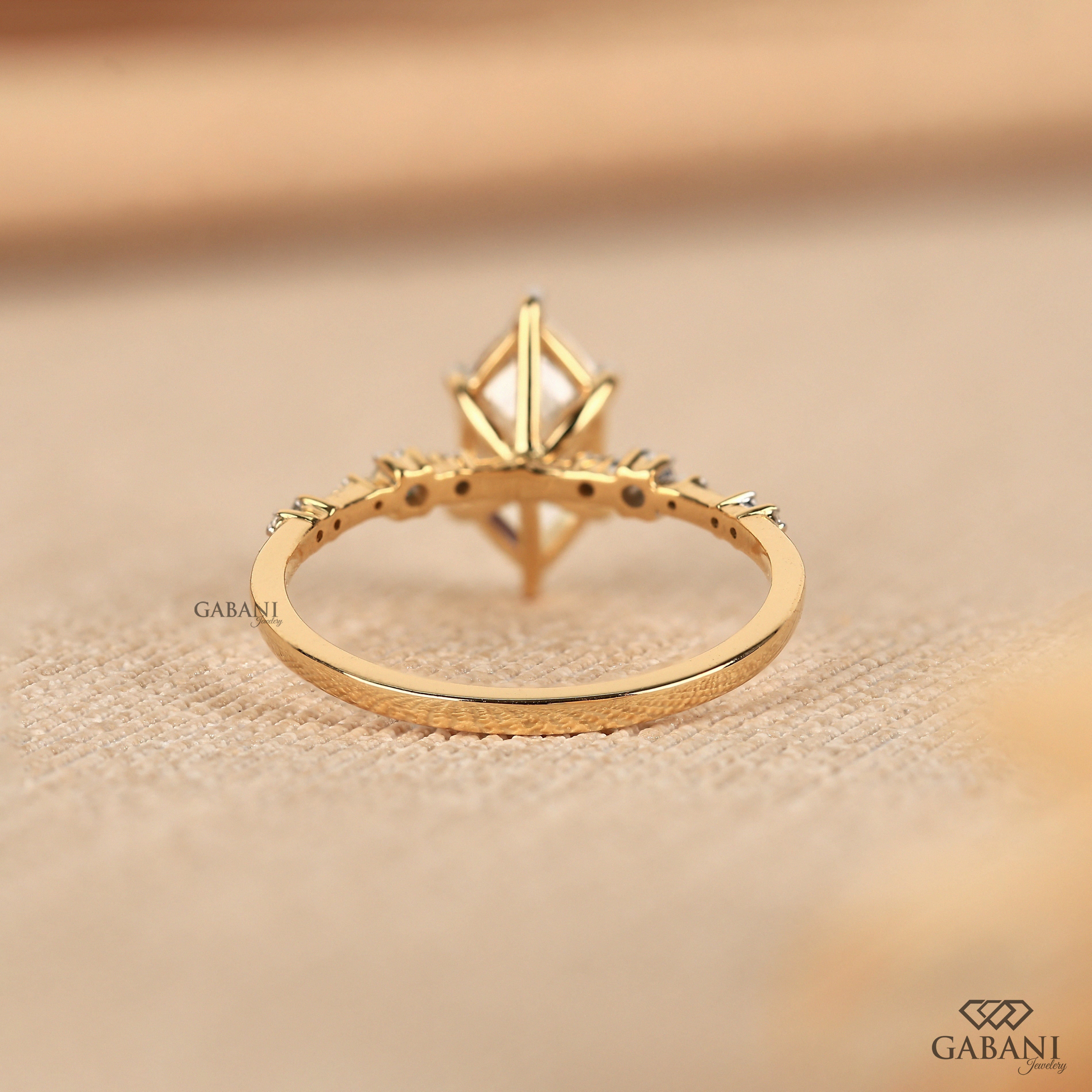 Dutch marquise lab grown diamond engagement ring with elongated geometric center stone, round side diamond accents and gold band.