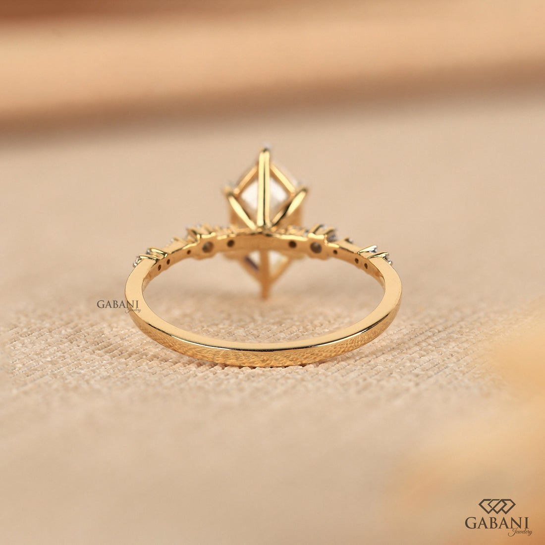 Dutch marquise lab grown diamond engagement ring with elongated geometric center stone, round side diamond accents and gold band.