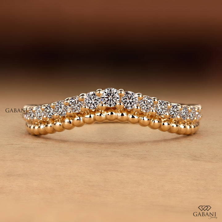 A close-up of a rose gold ring with a double row of round brilliant-cut diamonds, set against a warm brown and beige gradient background. The Gabani brand logo is visible in the bottom right corner.