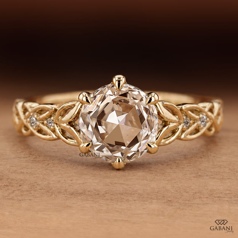 Oval rose cut lab grown diamond engagement ring with leaf vine band, round diamond accents, and six claw prong setting in 14K yellow gold.