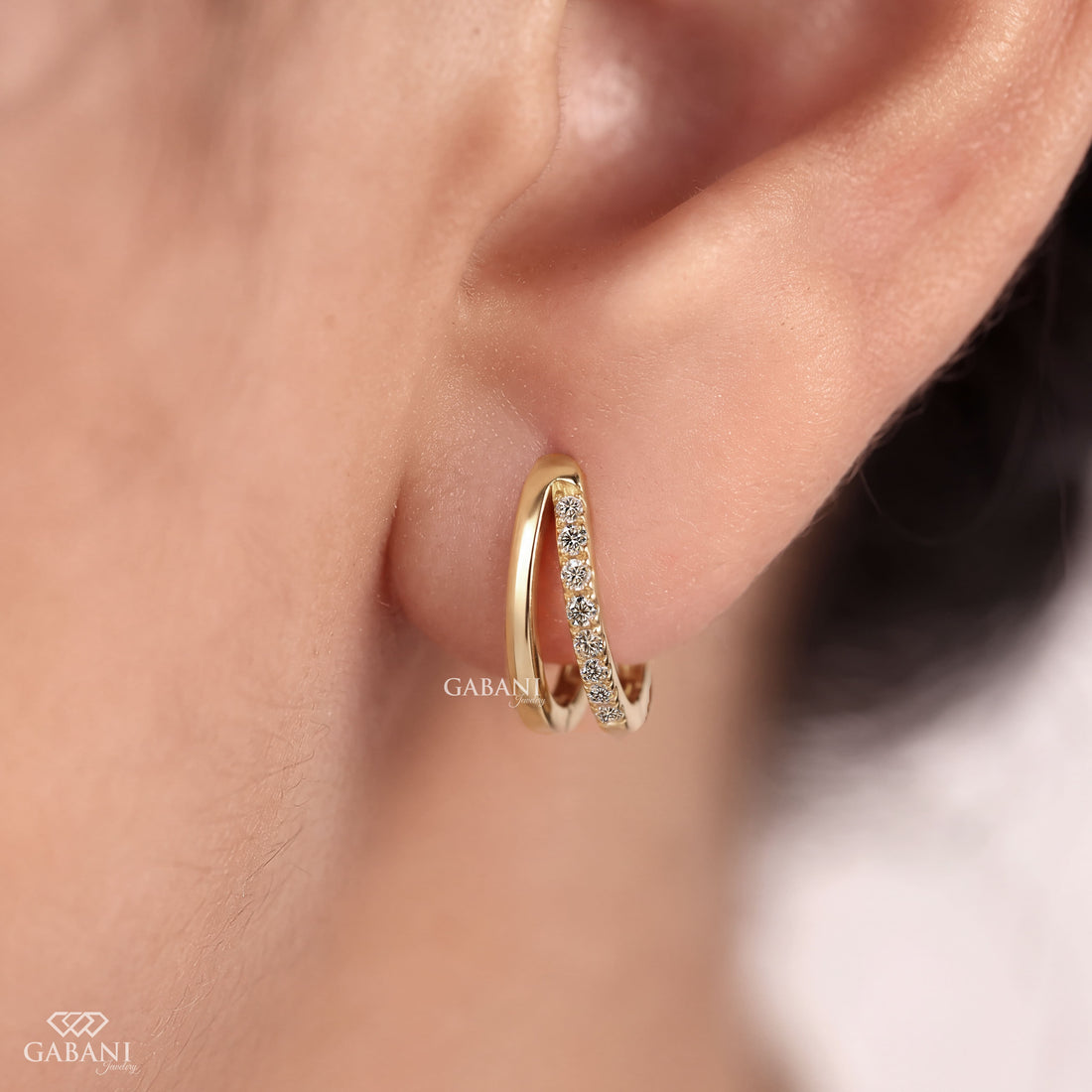 Round cut diamond double hoop huggie earrings in yellow gold with polished and diamond set rows and hinged click closure.