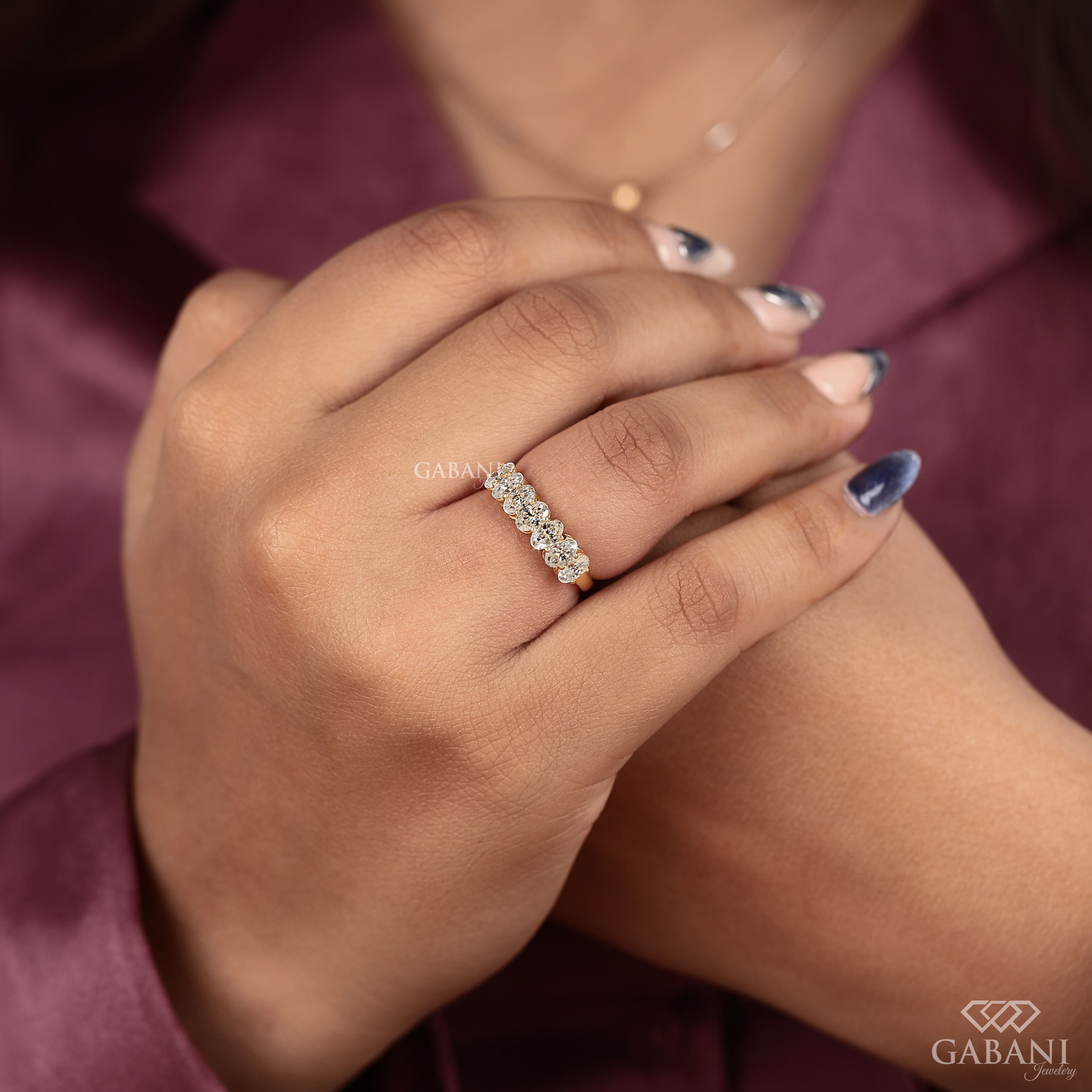 seven oval cut lab grown diamonds arranged in a prong set half eternity wedding band with polished 14K yellow gold.