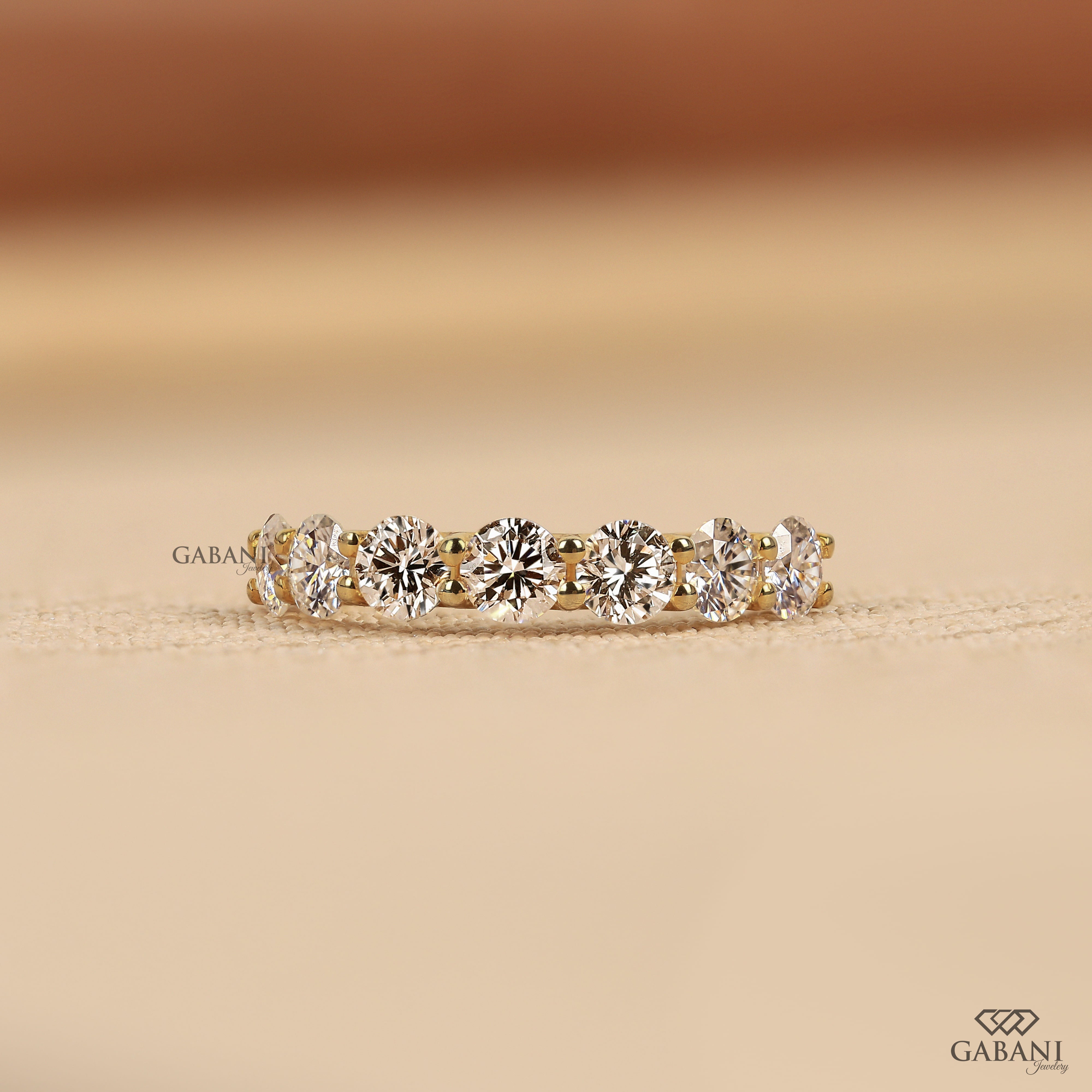 seven round cut lab grown diamonds in a yellow gold half eternity wedding band with open prong settings and a smooth shank.