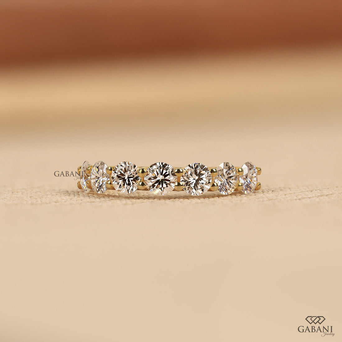 seven round cut lab grown diamonds in a yellow gold half eternity wedding band with open prong settings and a smooth shank.