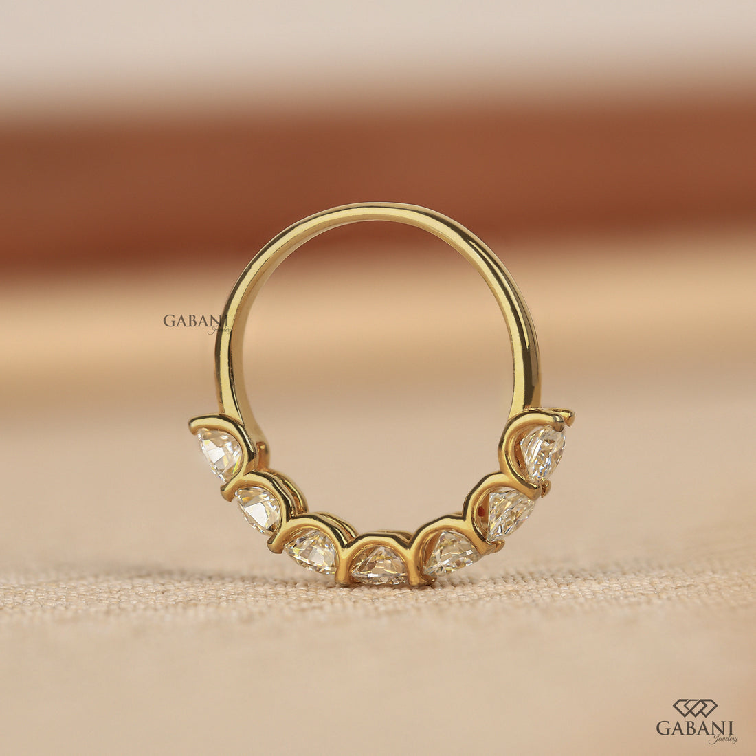 seven round cut lab grown diamonds in a yellow gold half eternity wedding band with open prong settings and a smooth shank.