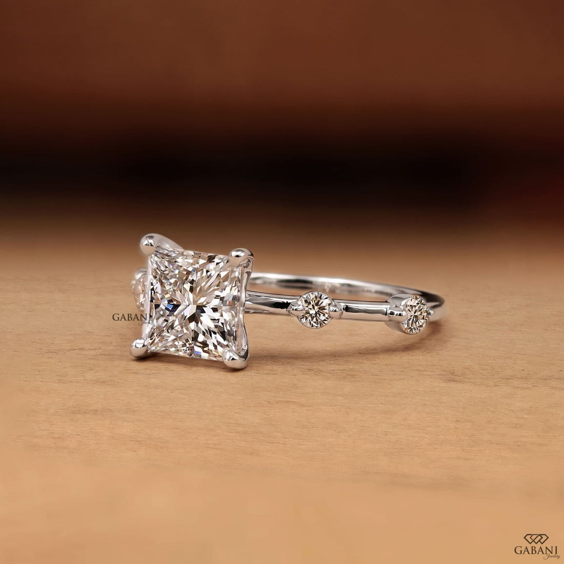 Princess cut lab grown diamond engagement ring in white gold with a four prong center setting and spaced round diamond side stones along the polished band.
