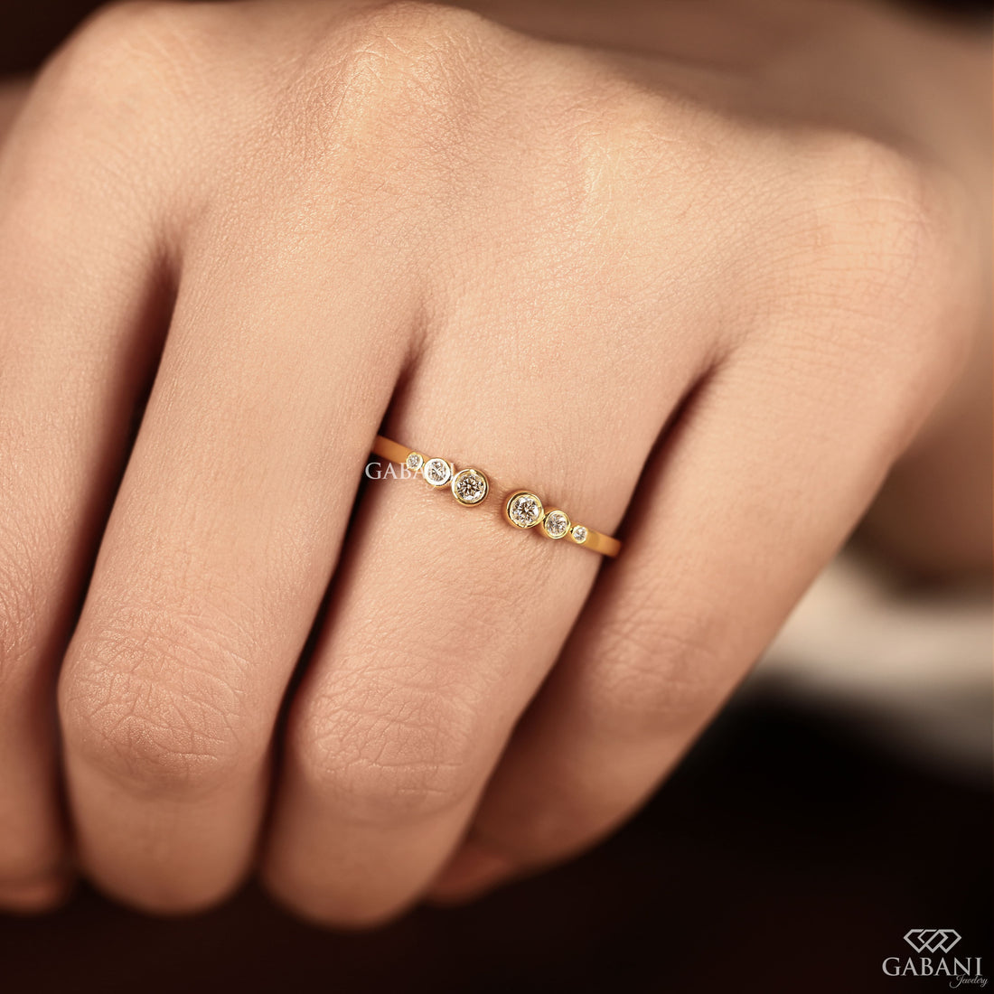 a round cut lab grown diamond open cuff band featuring six graduated bezel set diamonds in polished 14K yellow gold, a modern minimalist diamond wedding band by Gabani Jewelry.