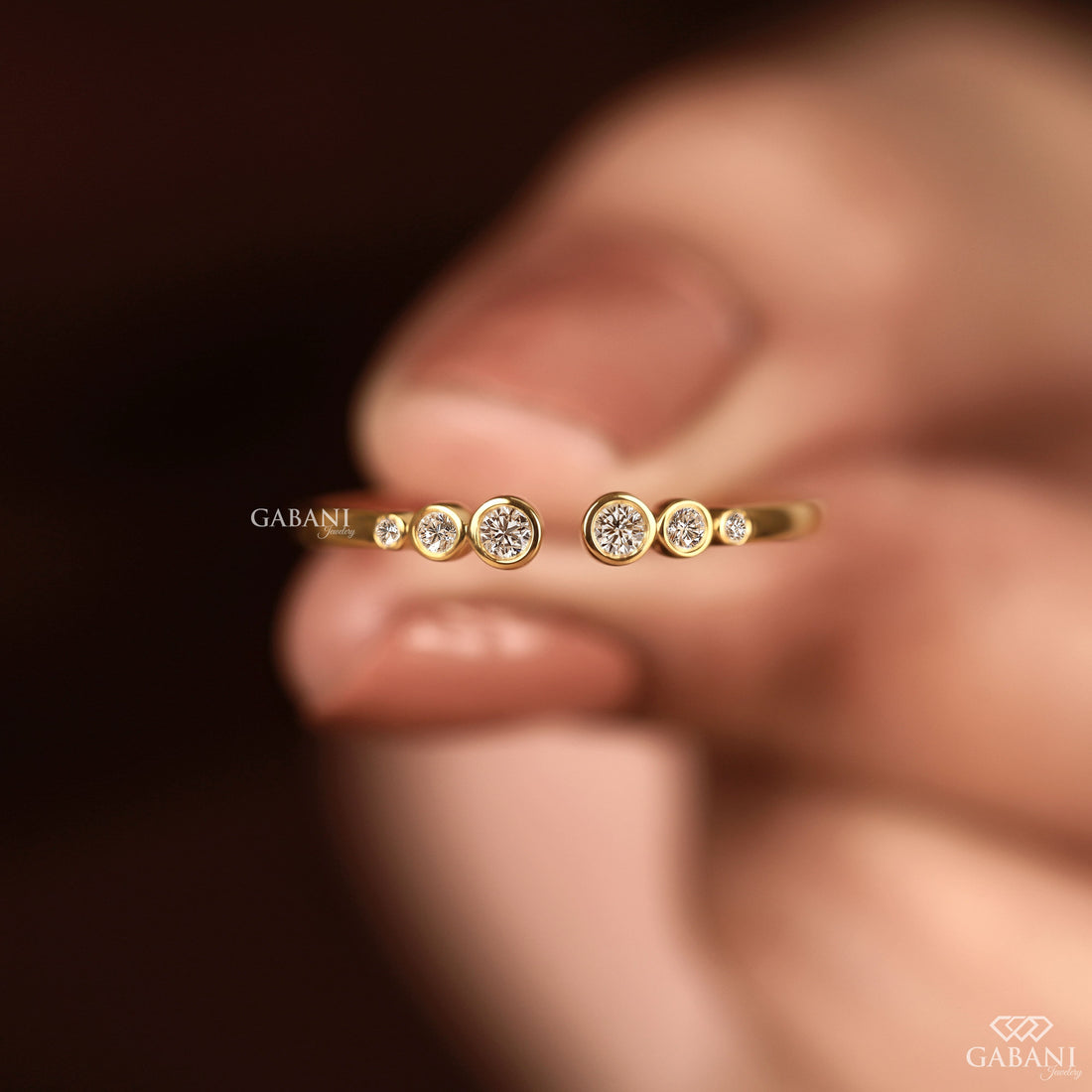 a round cut lab grown diamond open cuff band featuring six graduated bezel set diamonds in polished 14K yellow gold, a modern minimalist diamond wedding band by Gabani Jewelry.