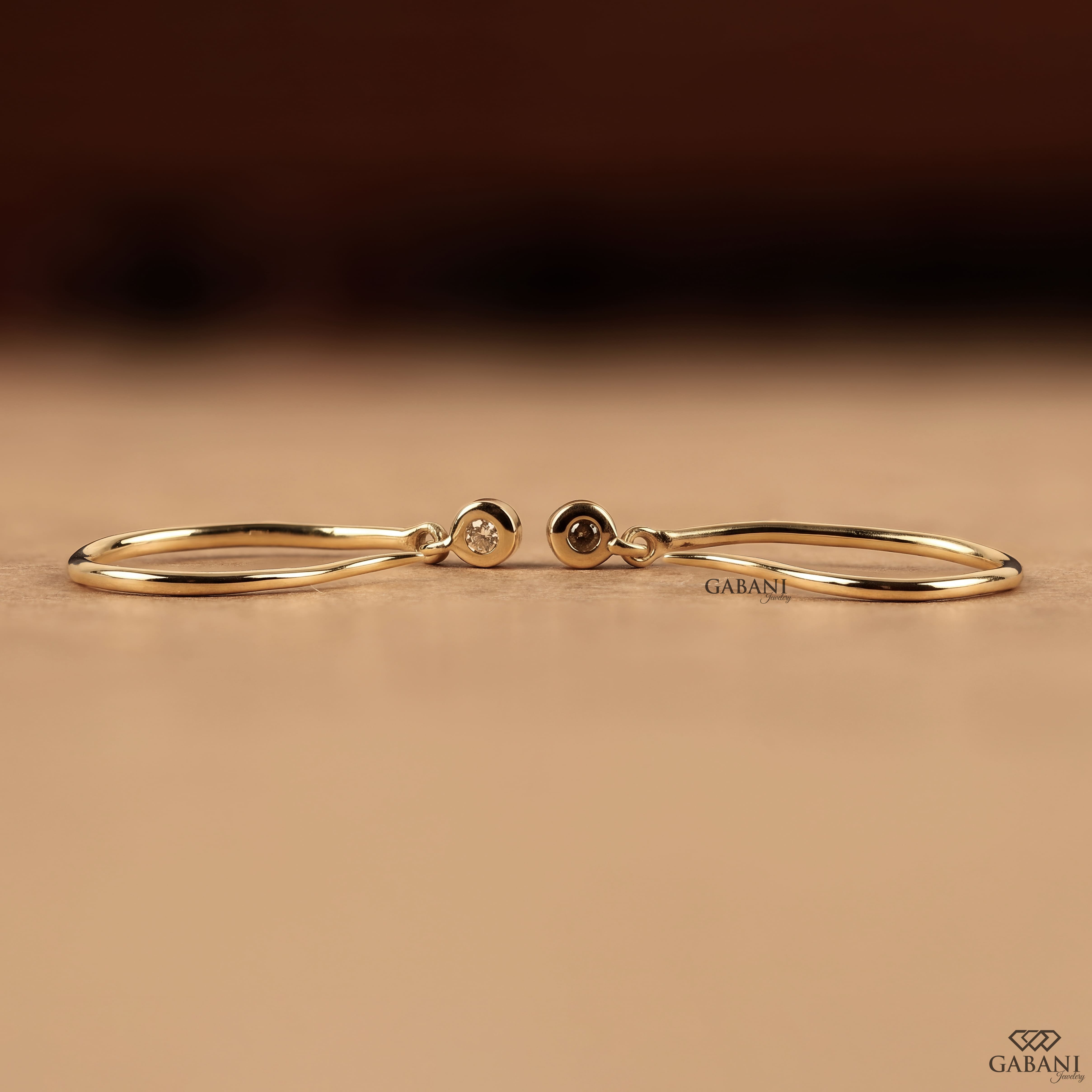 Round cut lab grown diamond hook earrings with 0.10 CTW, bezel set stones and a slim curved gold drop design for everyday wear.