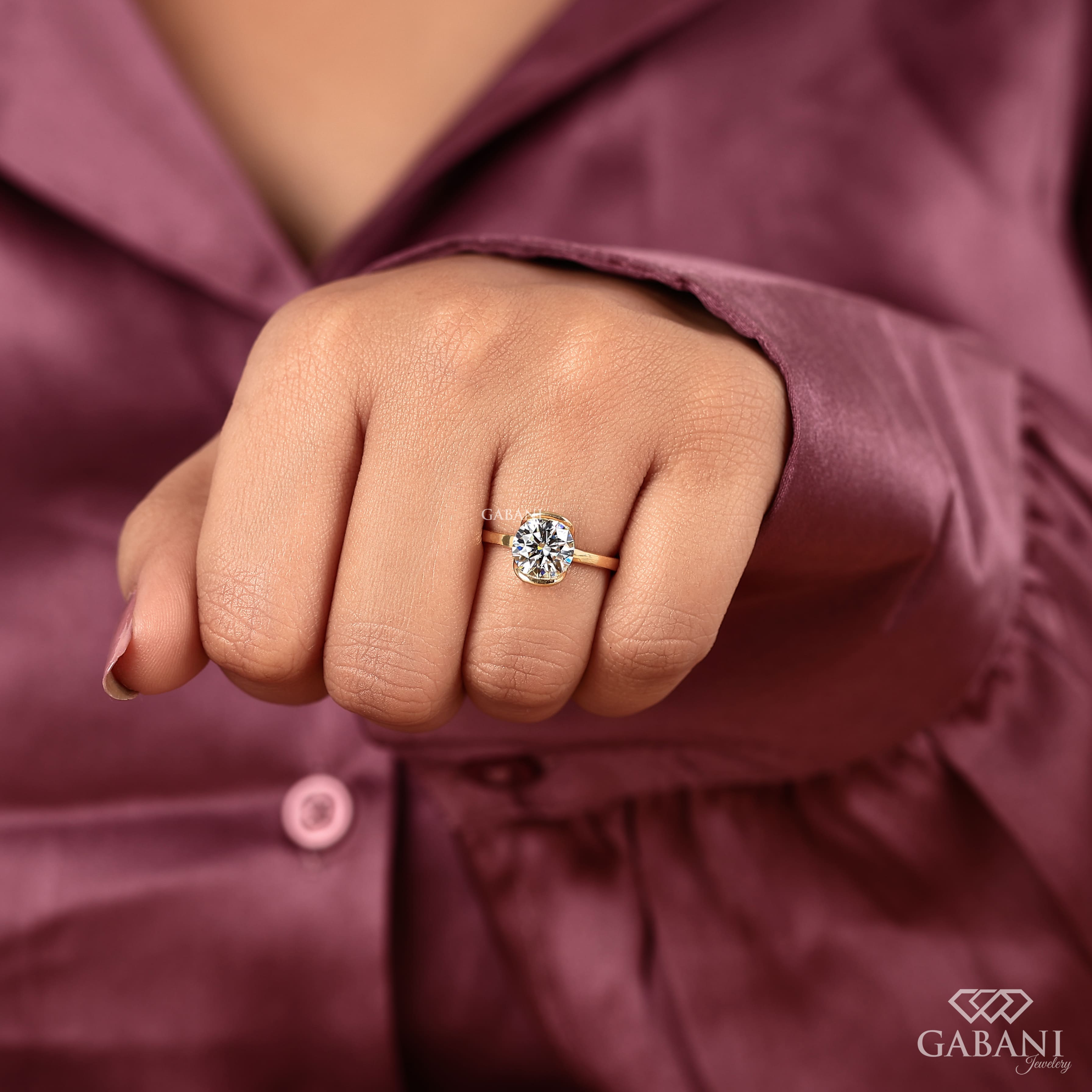 Round diamond half bezel solitaire engagement ring in yellow gold with a slim straight polished band.
