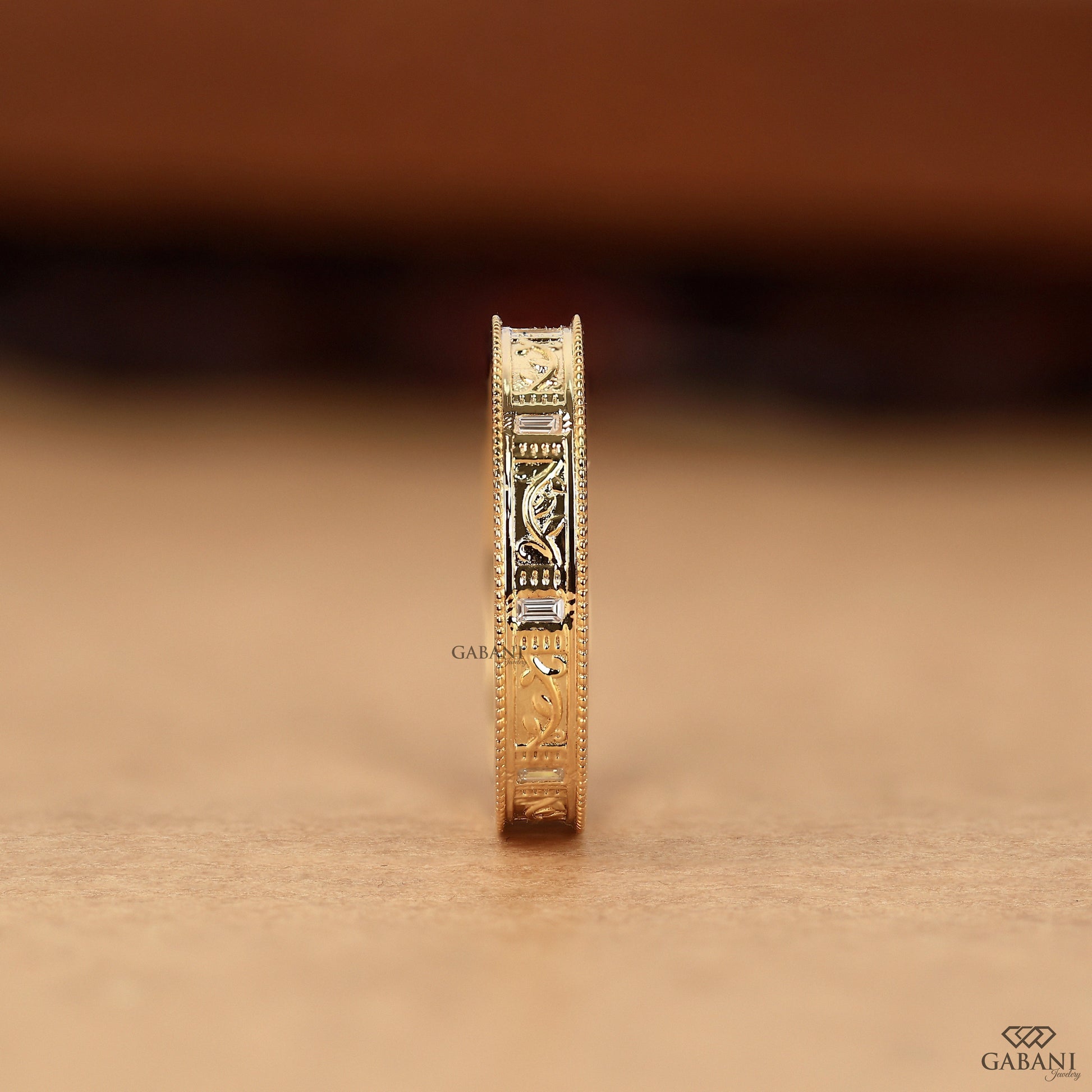 Macro detail of milgrain edge and leaf motif on yellow gold ring, highlighting texture, engraving, and subtle diamond sparkle