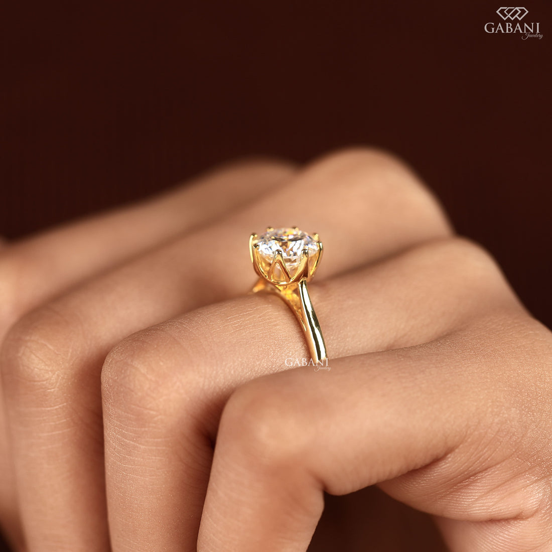 Shop a round Portuguese cut lab grown diamond solitaire engagement ring with a six-prong floral basket and polished yellow gold band.