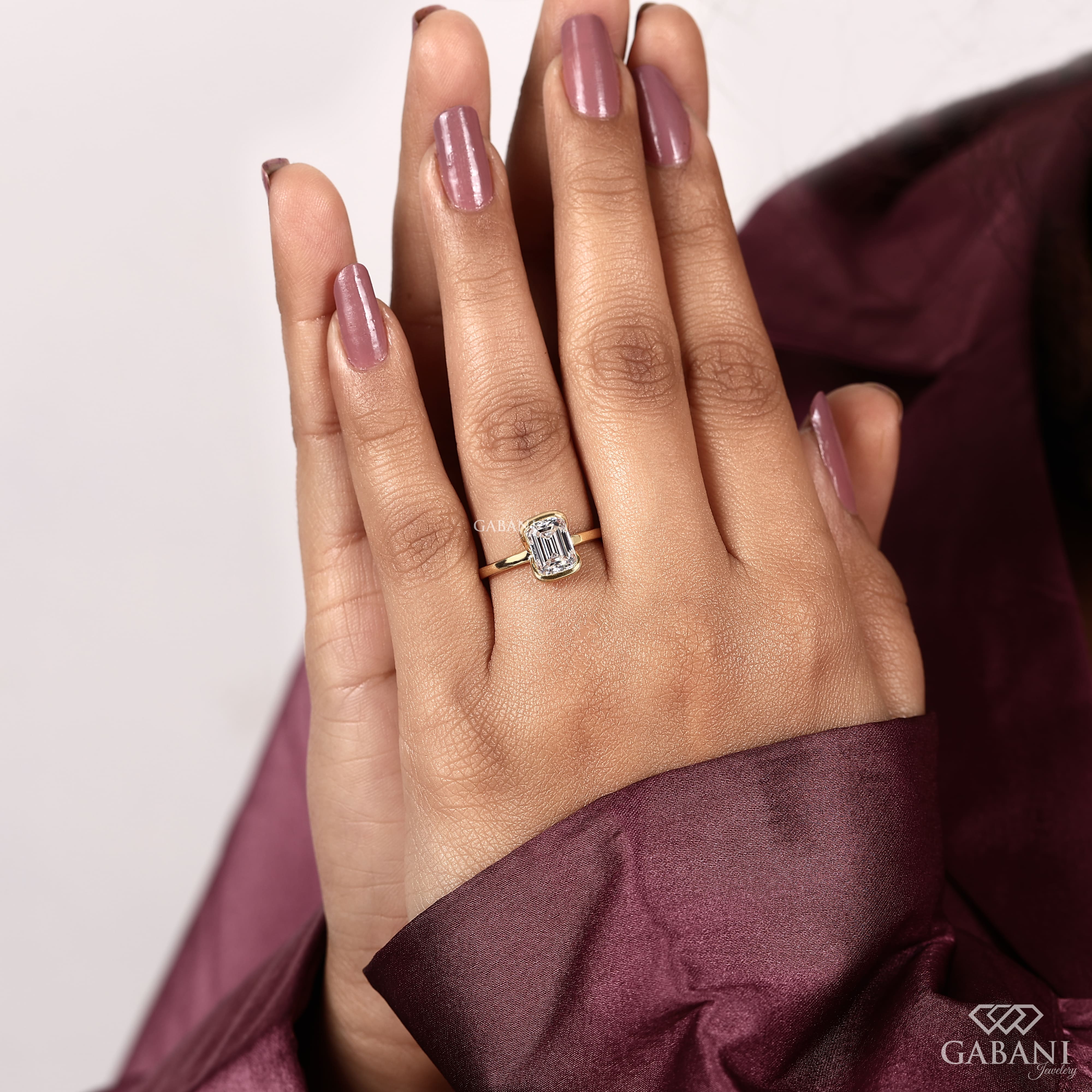 Front view of emerald cut lab grown diamond solitaire engagement ring with modern half bezel setting and polished 14K yellow gold band.