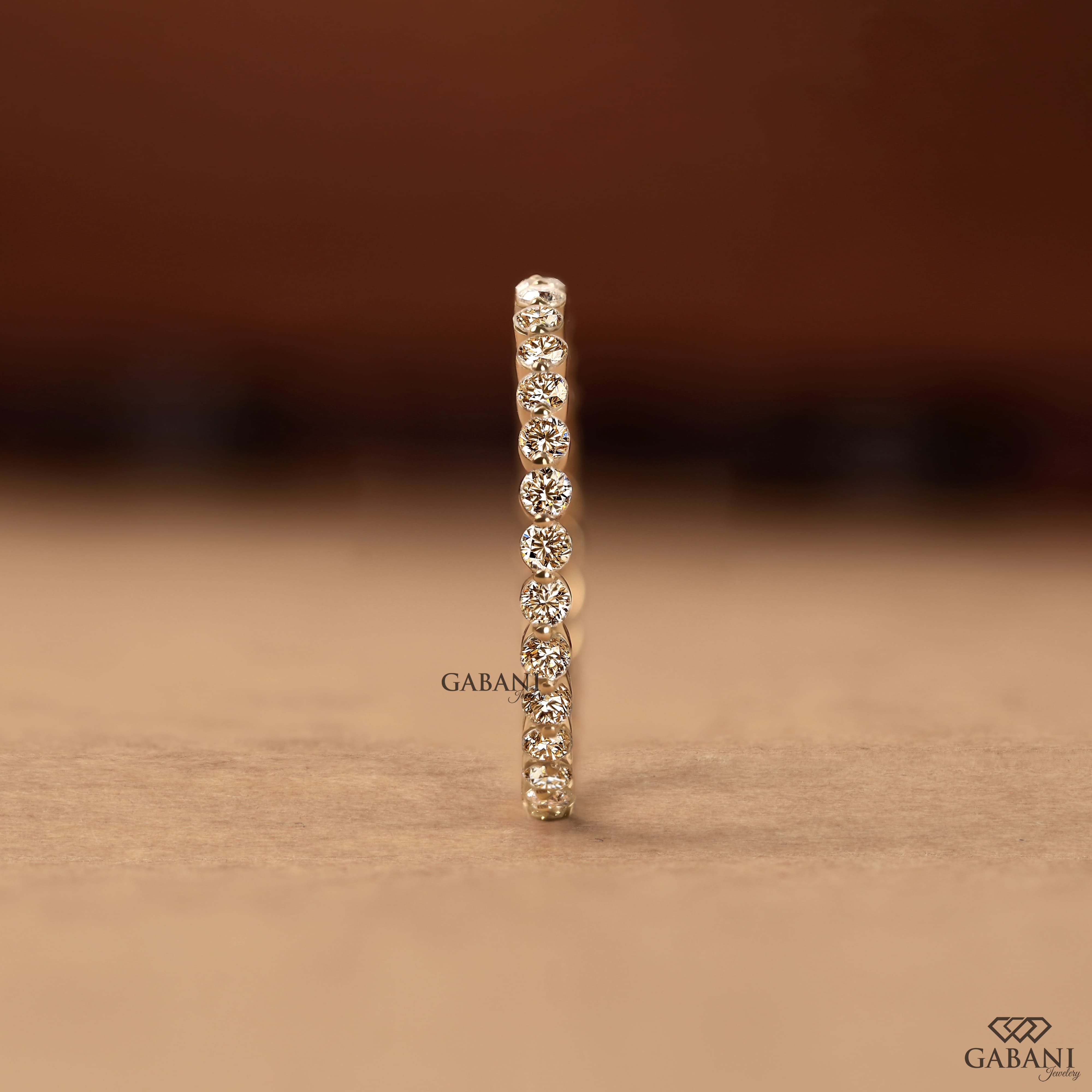 Round cut lab grown diamond bezel set eternity wedding band in solid yellow gold, stackable bridal and anniversary ring.