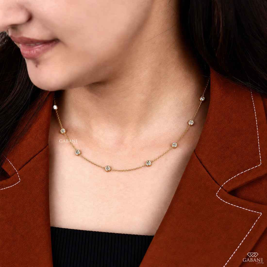 Yellow gold station necklace featuring evenly spaced round cut diamonds in full bezel settings along a delicate gold chain.