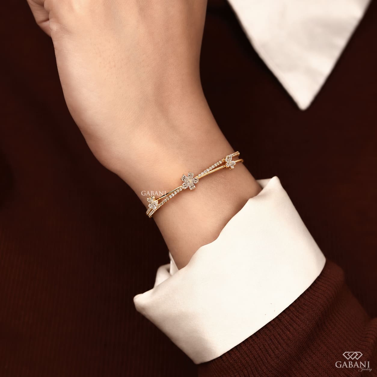 Yellow gold open cuff bangle bracelet featuring three pear cut diamond flower clusters and round pavé diamond accents.