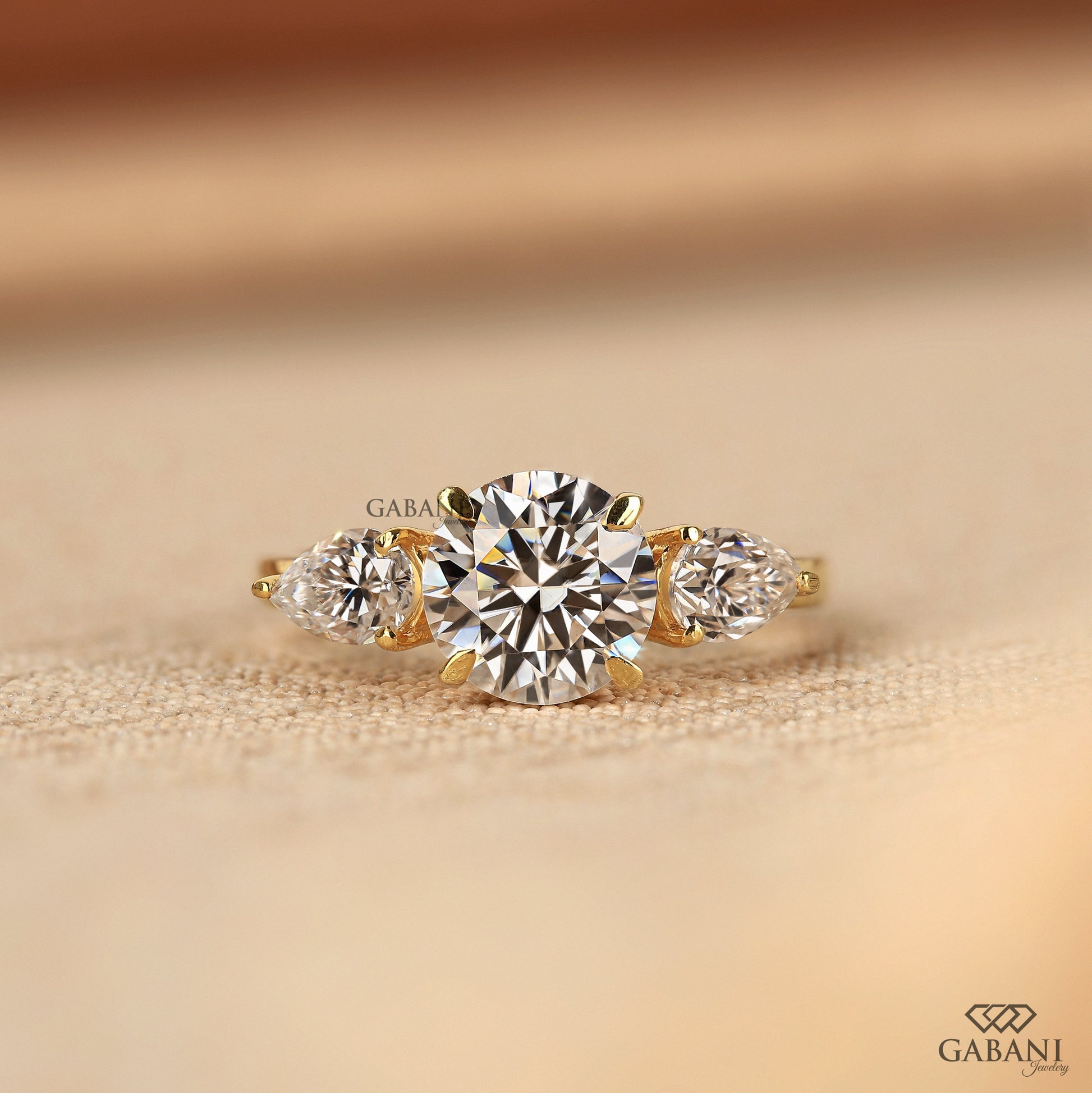 three stone lab grown diamond ring by Gabani Jewelry with round center and pear sides