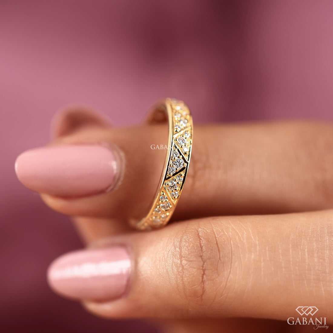 Round lab grown diamond wedding band with geometric triangular pattern and polished yellow gold setting.