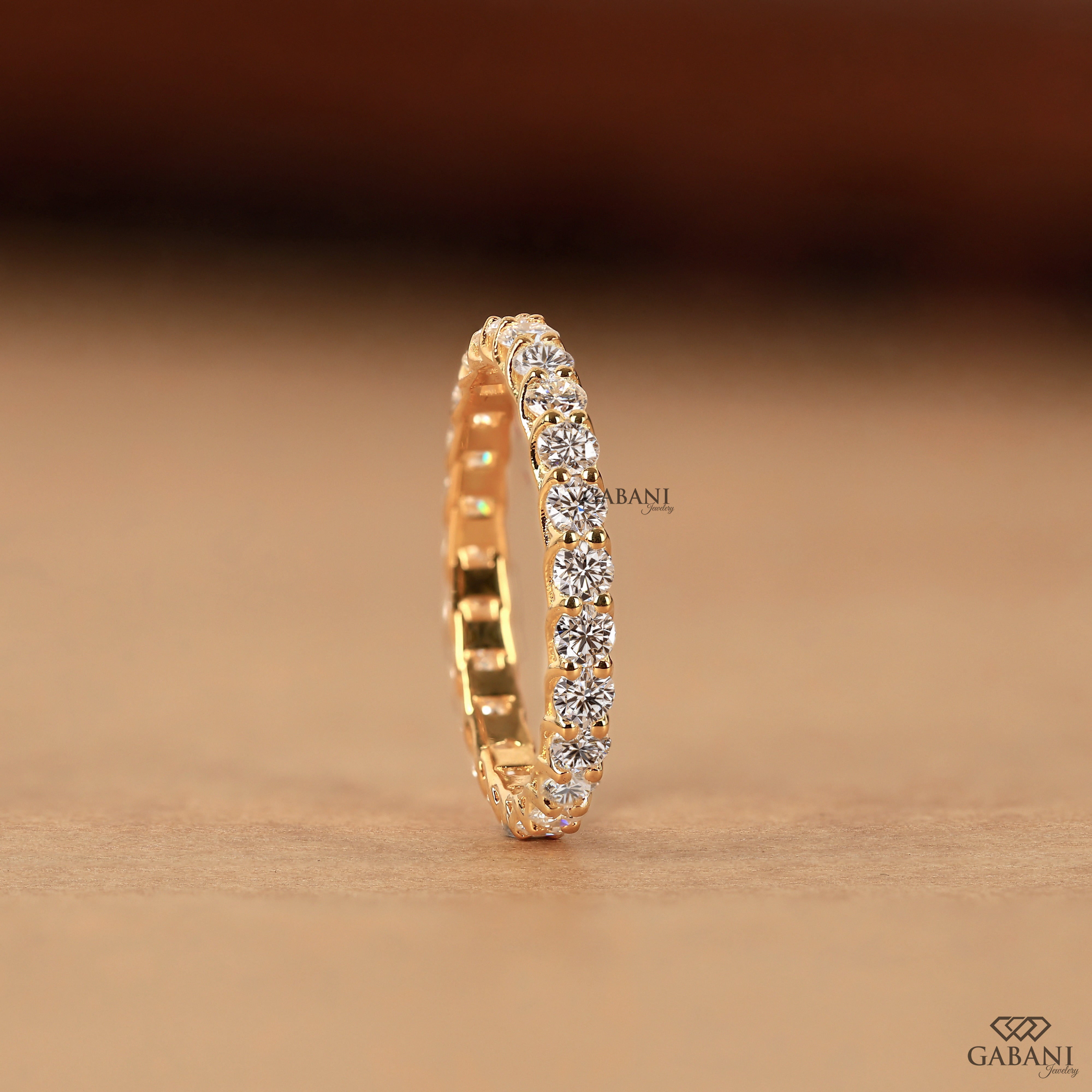 a round lab grown diamond full eternity band in 14K yellow gold, featuring sparkling shared prong set diamonds in a classic wedding band design by Gabani Jewelry.