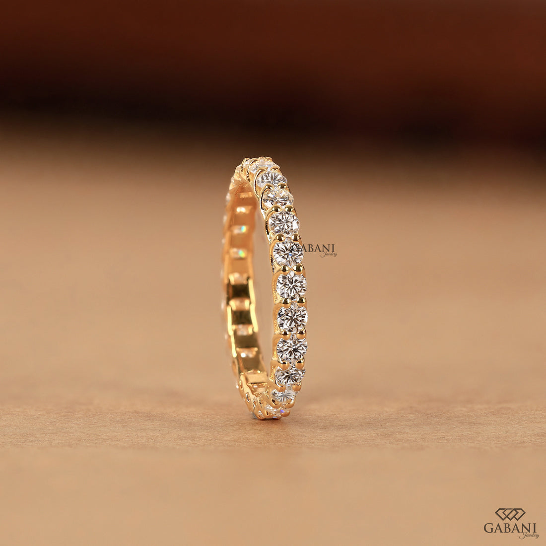 a round lab grown diamond full eternity band in 14K yellow gold, featuring sparkling shared prong set diamonds in a classic wedding band design by Gabani Jewelry.