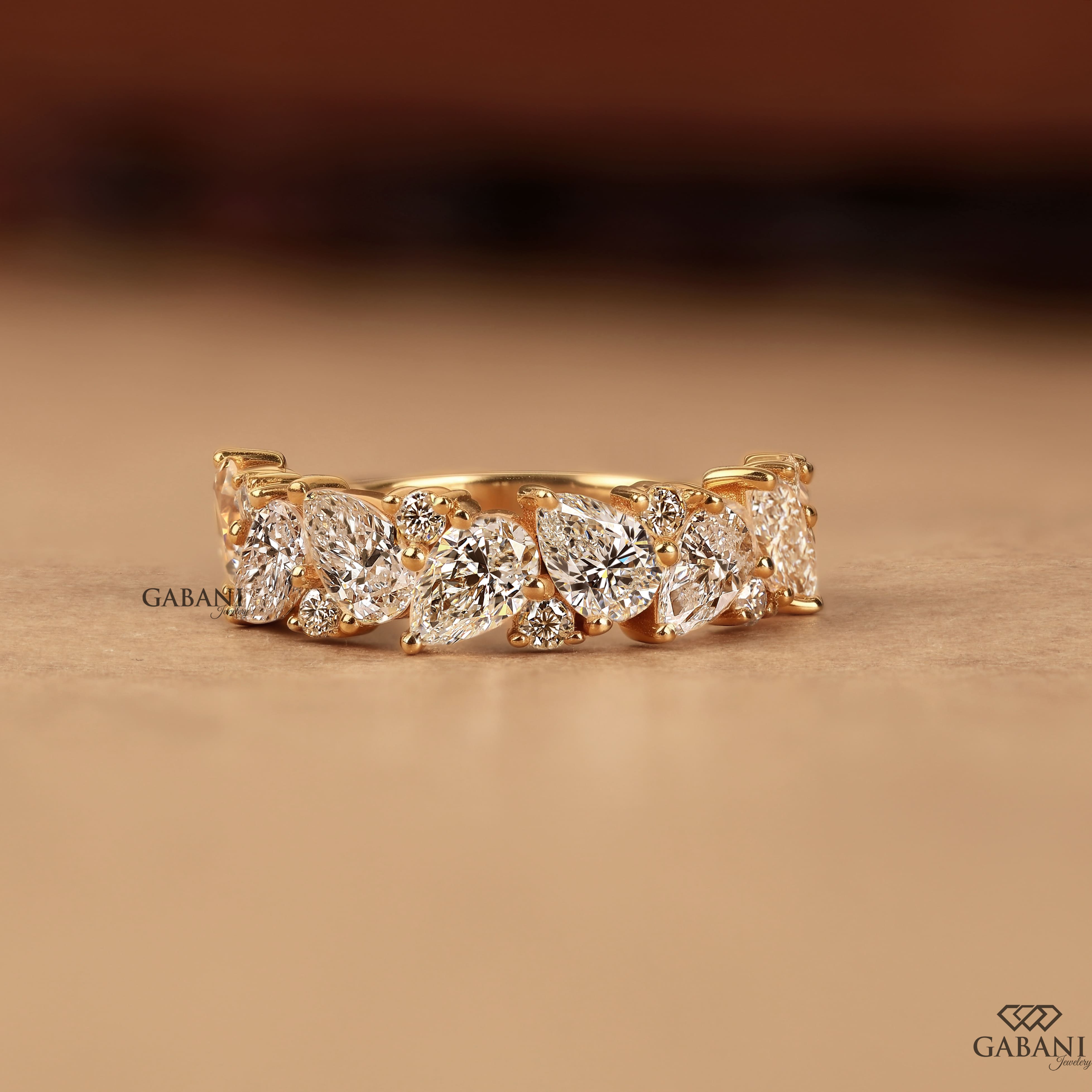 Pear and round lab grown diamond half eternity wedding band in yellow gold with alternating prong set diamond design.