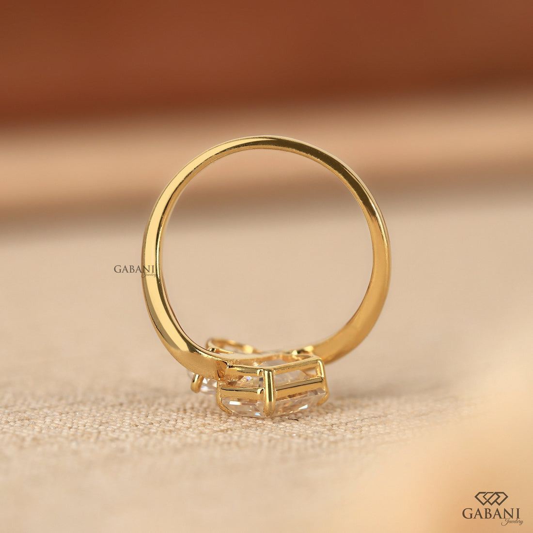 Pear and emerald cut lab grown diamond Toi et Moi ring with a curved yellow gold band, designed for engagement, anniversary, proposal, and statement wear.